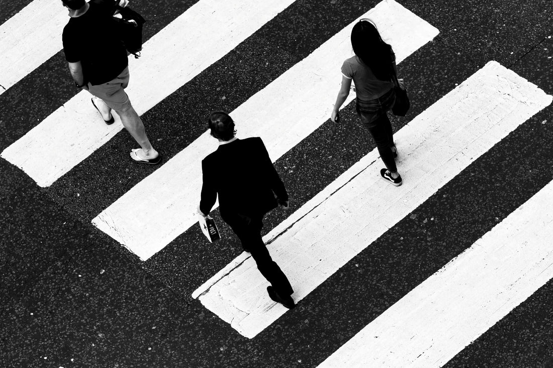 Three people cross over a pedestrian crossing.