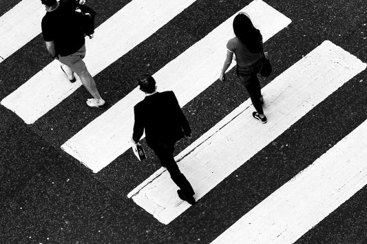 Three people cross over a pedestrian crossing.