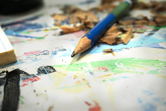Closeup of a pencil surrounded by pencil shavings on an artist's desk.